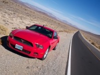Arty-farty shot of a red sportscar parked by the side of a very long, straight desert road