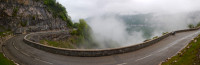 Wide shot of bike parked in middle of sweeping mountain corner, a cloud trying to eat the apex