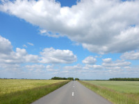 Dead straight road leading into the distance under a blue and white sky